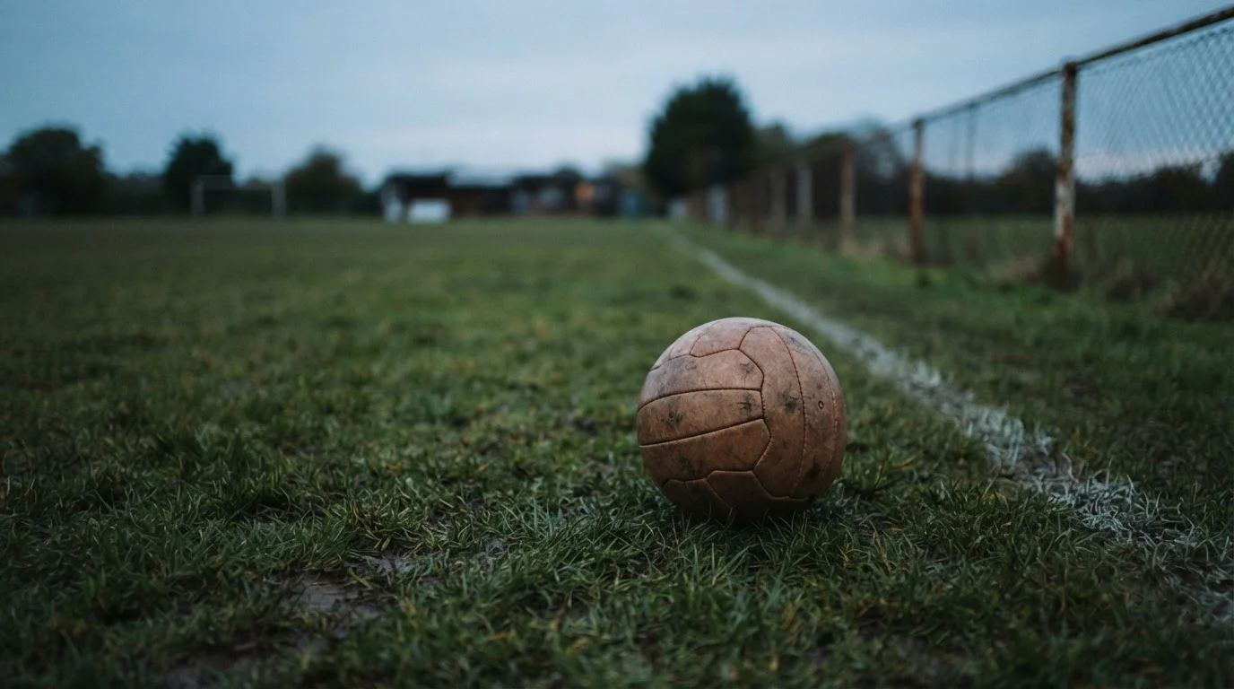 Balón de fútbol clásico sobre césped al atardecer, sin marcas visibles